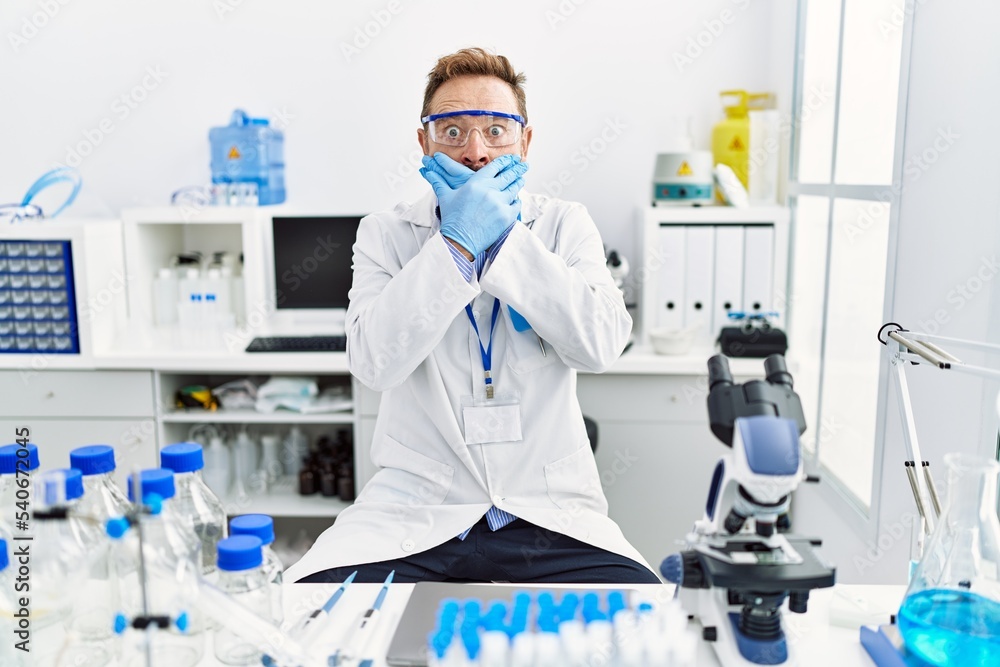 Middle age man working at scientist laboratory shocked covering mouth with hands for mistake. secret concept. Middle age man working at scientist laboratory shocked covering mouth with hands for mistake. secret concept.