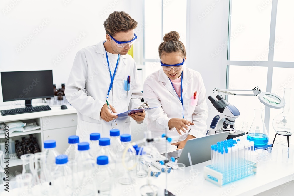 Fototapeta premium Man and woman wearing scientist uniform using laptop working at laboratory