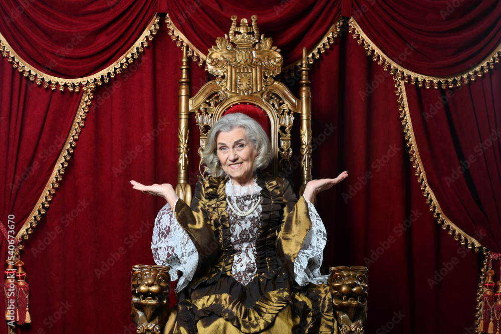 senior queen in a dress sits on a throne