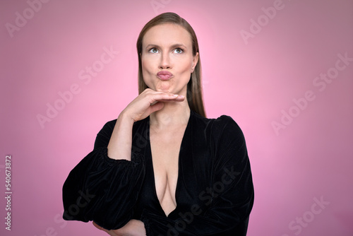 Beautiful woman pouting while standing against purple background