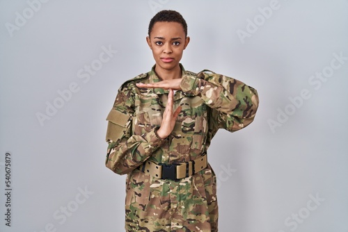 Beautiful african american woman wearing camouflage army uniform doing time out gesture with hands, frustrated and serious face