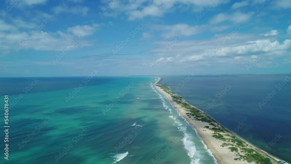 Aerial over the long sandy spit with a beach and azure water on a sunny summer day. Waves crashing to the shore. Relaxing calm atmosphere Aerial over the long sandy spit with a beach and azure water on a sunny summer day. Waves crashing to the shore. Relaxing calm atmosphere