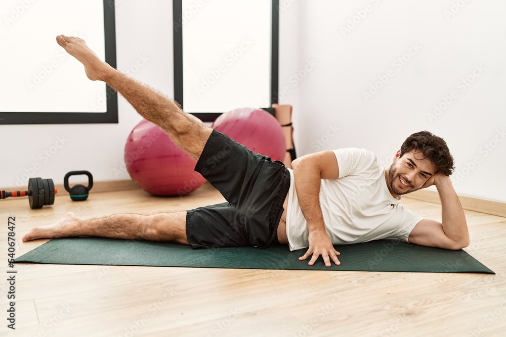 Young hispanic man smiling confident training abs exercise at sport center