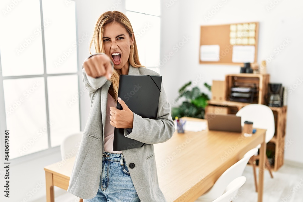 Blonde business woman at the office pointing displeased and frustrated to the camera, angry and furious with you Blonde business woman at the office pointing displeased and frustrated to the camera, angry and furious with you