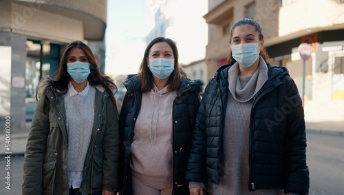 Mother and daugthers wearing medical mask standing together at street
