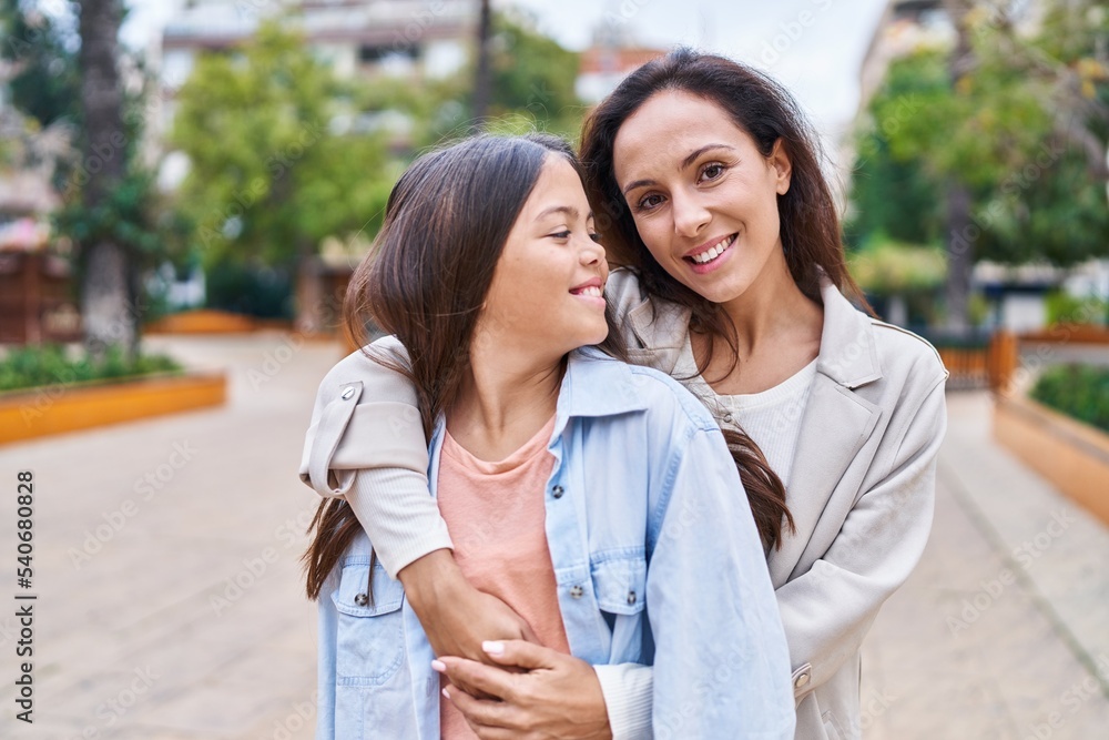 Woman and girl mother and daughter hugging each other at park Woman and girl mother and daughter hugging each other at park