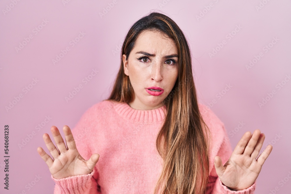Young hispanic woman standing over pink background moving away hands palms showing refusal and denial with afraid and disgusting expression. stop and forbidden. Young hispanic woman standing over pink background moving away hands palms showing refusal and denial with afraid and disgusting expression. stop and forbidden.