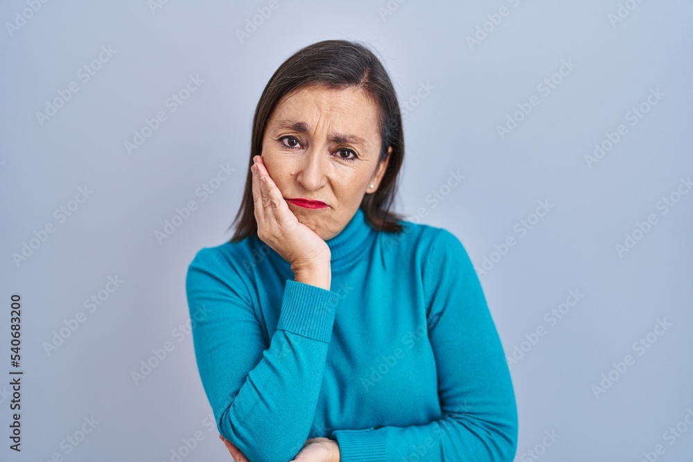 Middle age hispanic woman standing over isolated background thinking looking tired and bored with depression problems with crossed arms. Middle age hispanic woman standing over isolated background thinking looking tired and bored with depression problems with crossed arms.