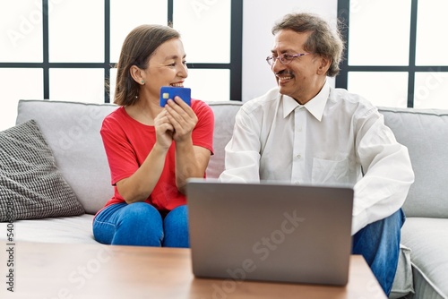 Middle age man and woman couple smiling confident using laptop and credit card at home