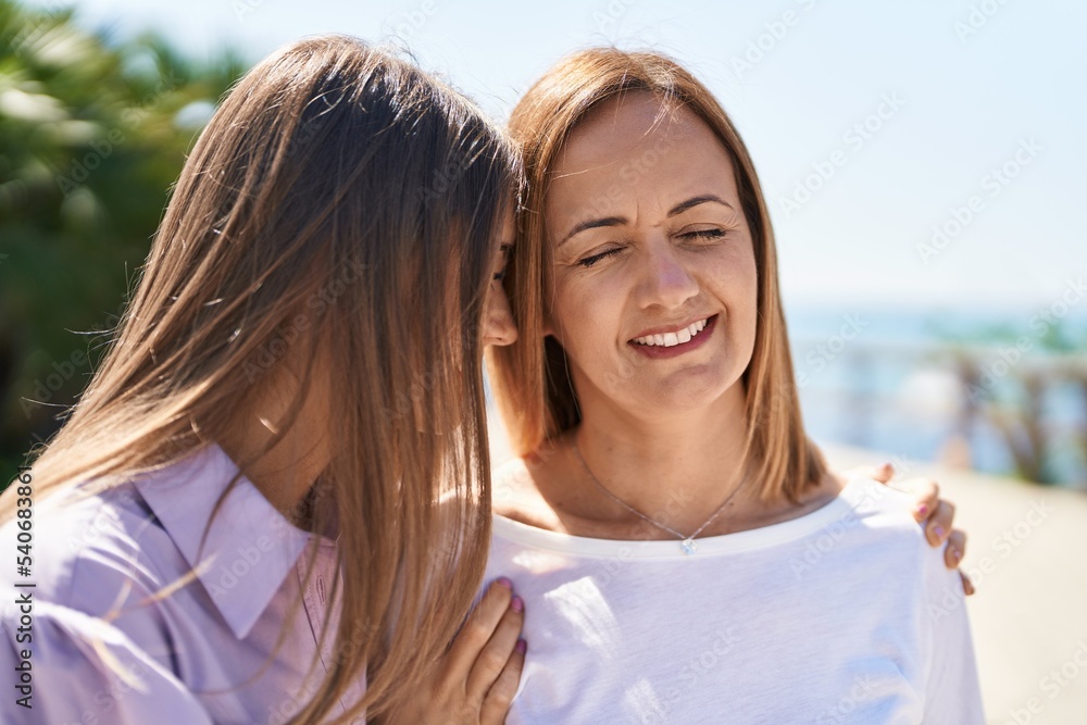 Two women mother and daughter standing together at seaside
