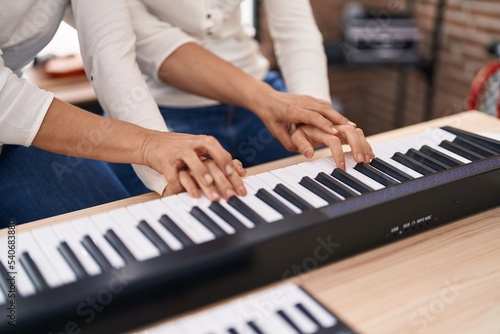 Two women musicians having piano lesson at music studio
