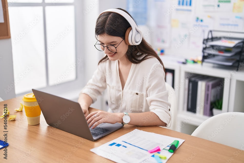 Young caucasian woman business worker using laptop and headphones working at office Young caucasian woman business worker using laptop and headphones working at office