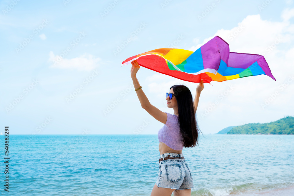 lesbian woman with LGBTQ flag on beach, she shows her liking or homosexuality