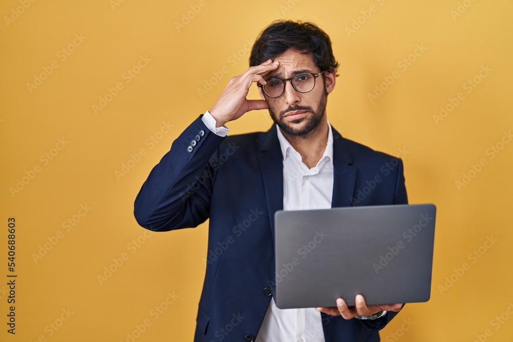 Handsome latin man working using computer laptop worried and stressed about a problem with hand on forehead, nervous and anxious for crisis Handsome latin man working using computer laptop worried and stressed about a problem with hand on forehead, nervous and anxious for crisis