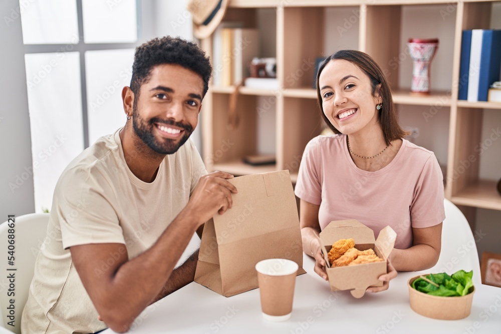 Man and woman couple sitting on table eating take away food at home