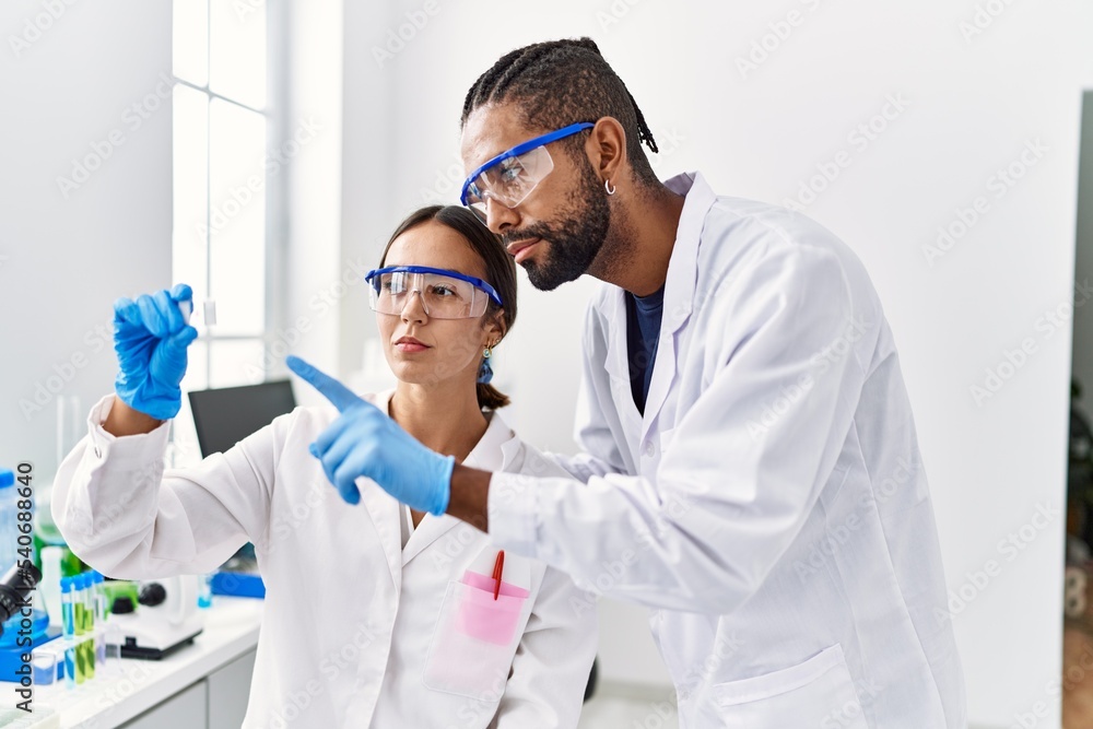 Man and woman scientist partners looking sample working at laboratory Man and woman scientist partners looking sample working at laboratory