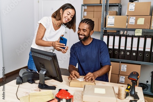 Photo Man and woman business partners using smartphone and packing order at storehouse