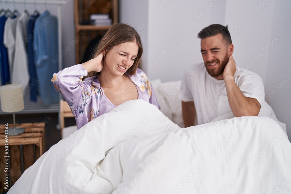 Man and woman couple suffering for neck injury sitting on bed at bedroom Man and woman couple suffering for neck injury sitting on bed at bedroom