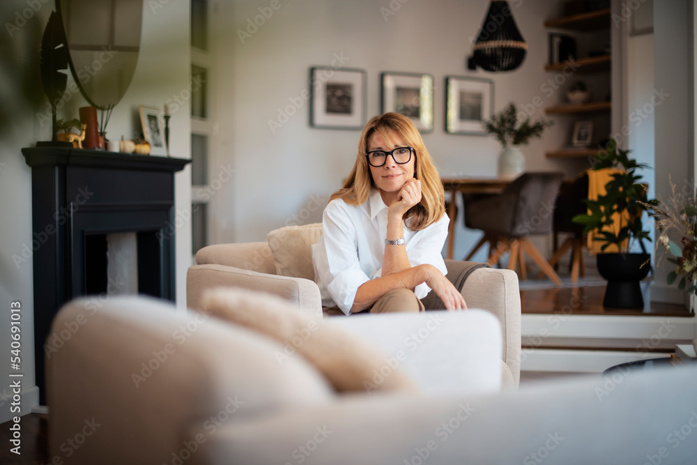Beautiful woman wearing casual clothes while sitting in an armchair at home Beautiful woman wearing casual clothes while sitting in an armchair at home