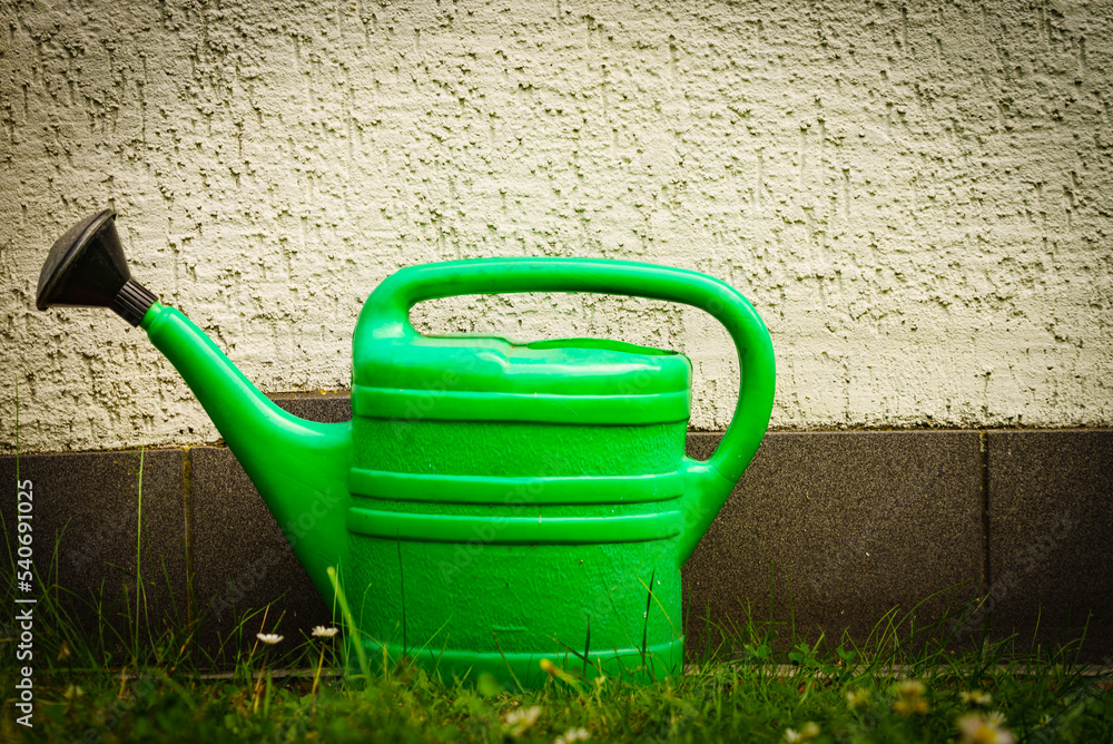 Watering green can on garden plot Watering green can on garden plot