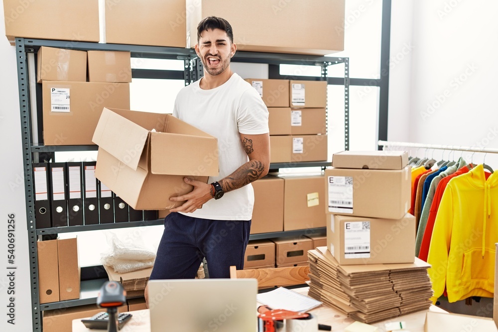 Young hispanic man working at small business ecommerce winking looking at the camera with sexy expression, cheerful and happy face. Young hispanic man working at small business ecommerce winking looking at the camera with sexy expression, cheerful and happy face.