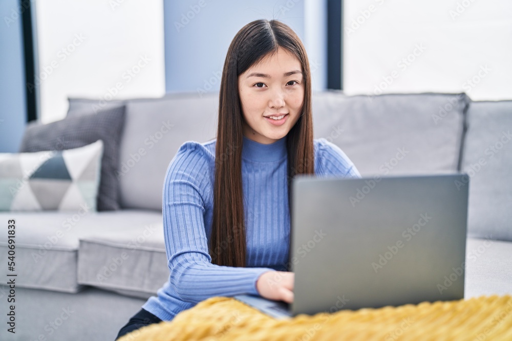 Chinese woman using laptop sitting on floor at home Chinese woman using laptop sitting on floor at home