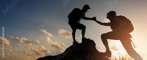 hikers team climbing up mountain cliff at sunset. giving helping hand. teamwork and assistance concept. banner with copy space