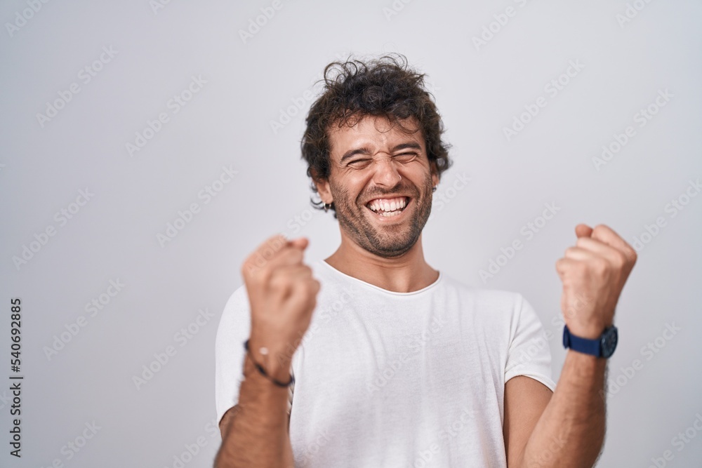 Young hispanic man standing with winner expression over isolated white background Young hispanic man standing with winner expression over isolated white background