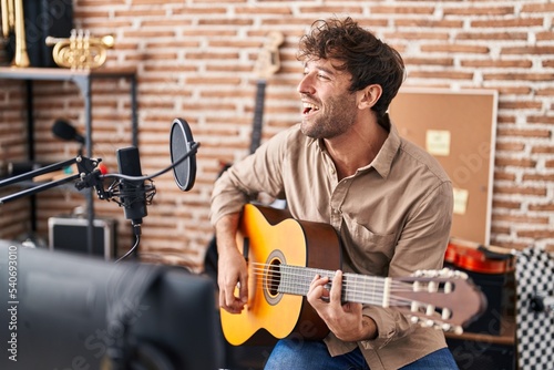 Young man musician singing song playing classical guitar at music studio photo