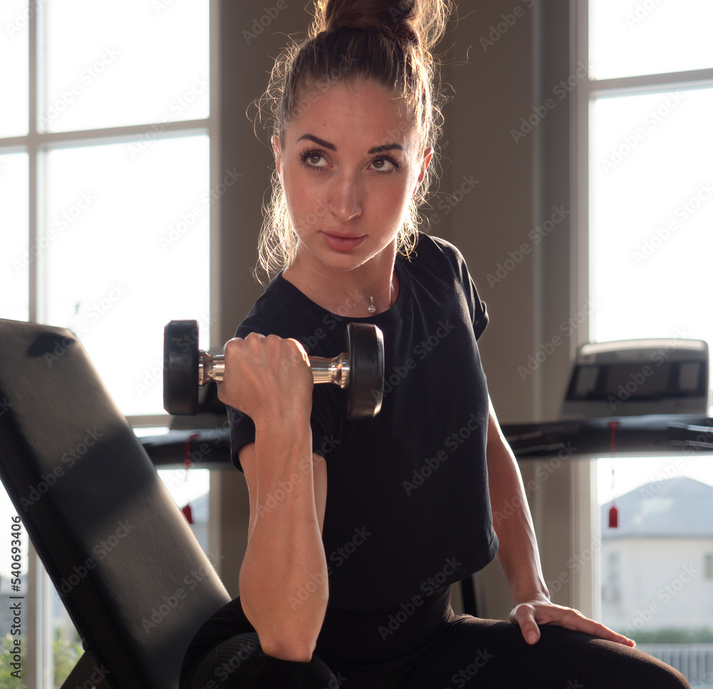 Beautiful athletic muscular woman pumps up the muscles by one arm lifts