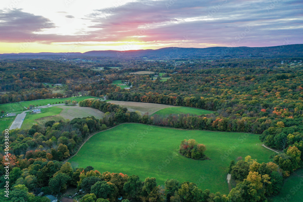 Obraz premium Brilliant Sunset in early fall over Wantage Township Sussex County NJ with large fields and foliage and Kittatiny Mountains in background aerial