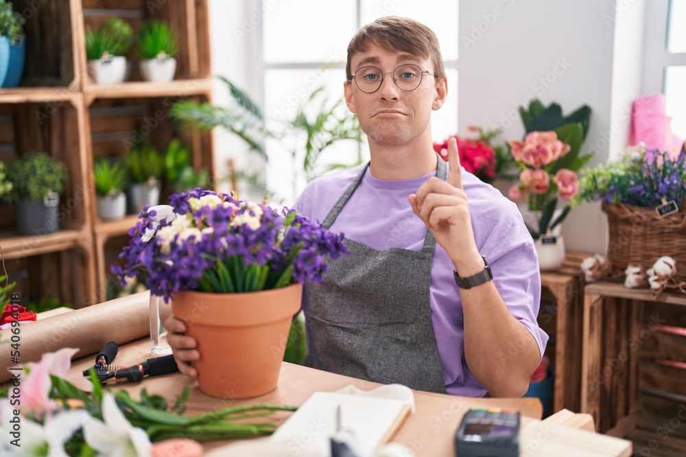 Caucasian blond man working at florist shop pointing up looking sad and upset, indicating direction with fingers, unhappy and depressed.