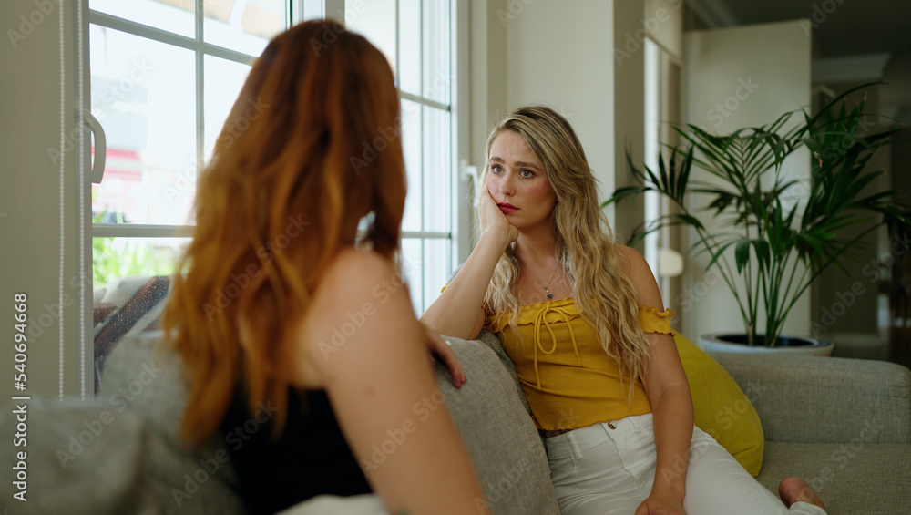 © Krakenimages.com - Two women sitting on sofa speaking at home