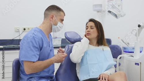 Latin american woman complains of toothache to dentist at dental clinic office