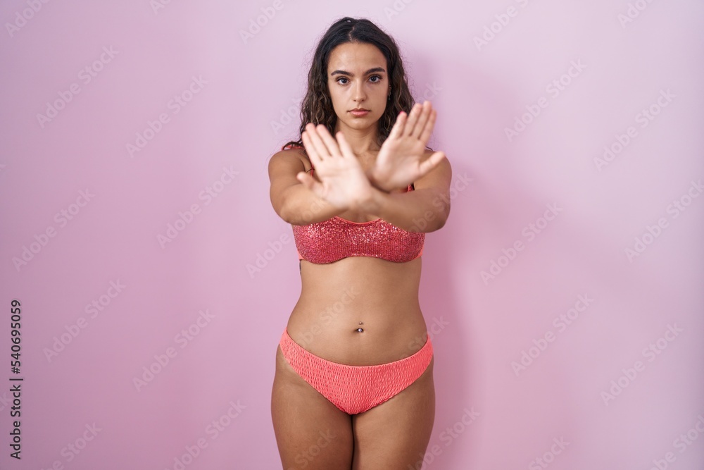 Young hispanic woman wearing lingerie over pink background rejection expression crossing arms and palms doing negative sign, angry face Young hispanic woman wearing lingerie over pink background rejection expression crossing arms and palms doing negative sign, angry face
