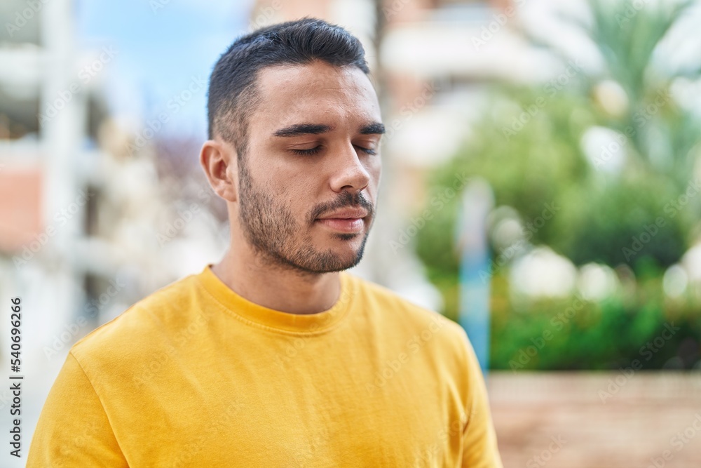 Fototapeta premium Young hispanic man breathing with closed eyes at street