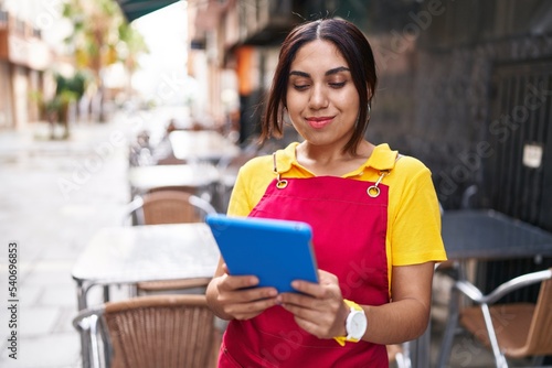 Young beautiful arab woman waitress smiling confident using touchpad at coffee shop terrace