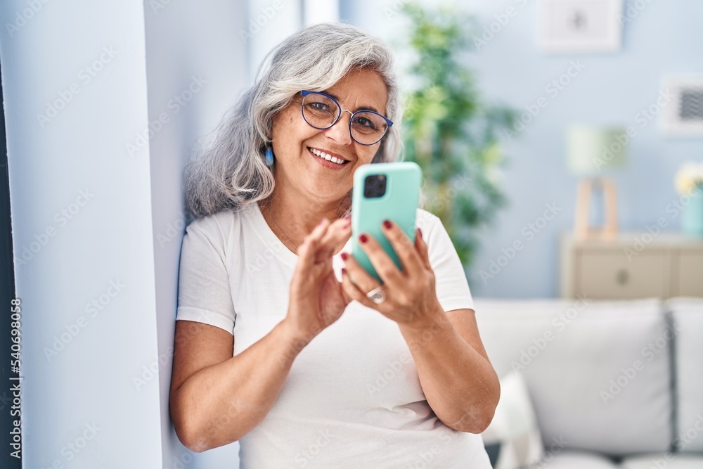 Middle age woman using smartphone standing at home Middle age woman using smartphone standing at home