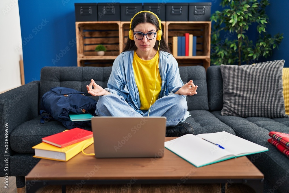 © Krakenimages.com - Young hispanic woman studying using computer laptop and headphones skeptic and nervous, frowning upset because of problem. negative person.