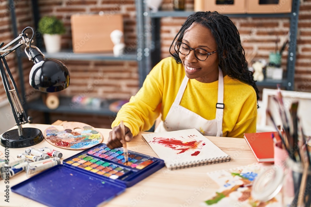 Fototapeta premium African american woman artist smiling confident drawing on notebook at art studio