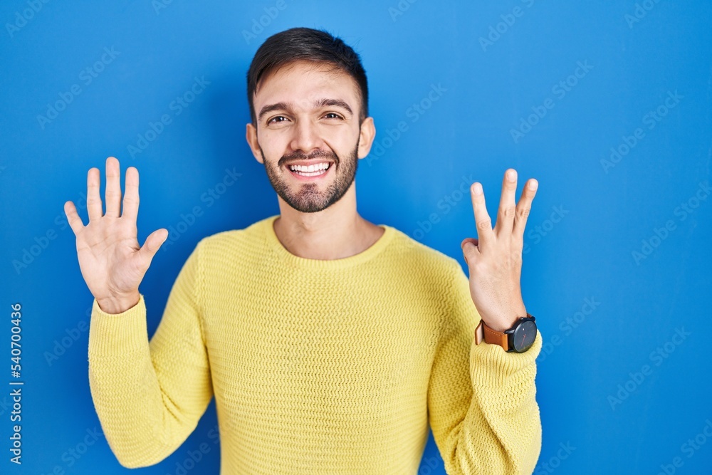 Hispanic man standing over blue background showing and pointing up with fingers number eight while smiling confident and happy. Hispanic man standing over blue background showing and pointing up with fingers number eight while smiling confident and happy.