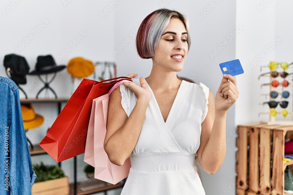Young caucasian customer woman holding shopping bags and credit card at clothing store. Young caucasian customer woman holding shopping bags and credit card at clothing store.