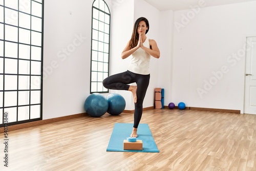 Middle age hispanic woman training yoga at sport center