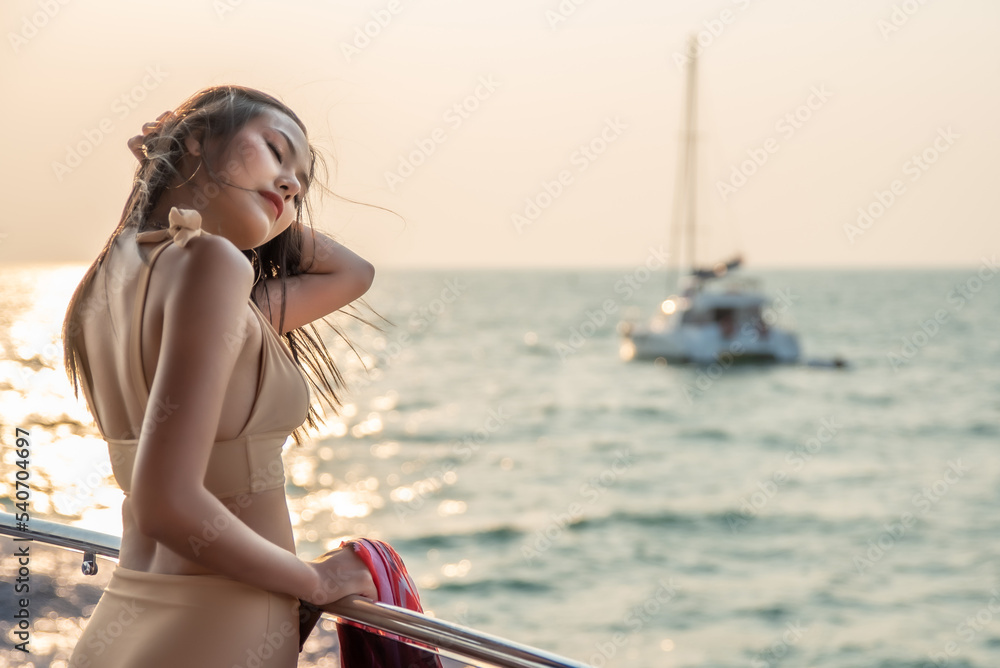 Portrait of a beautiful asian girl on a yacht at sunset. Woman enjoying travel and vacation on Cruise ship. Concept luxury travel and lifestyle concept.