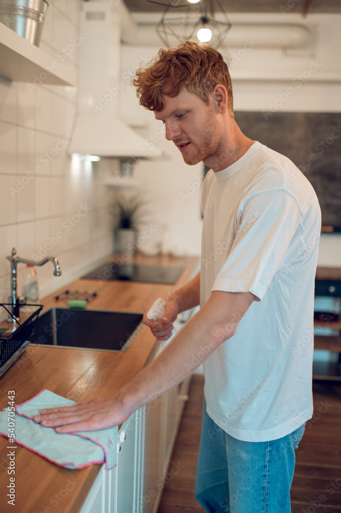 Man doing some housework and cleaning some surfaces Man doing some housework and cleaning some surfaces