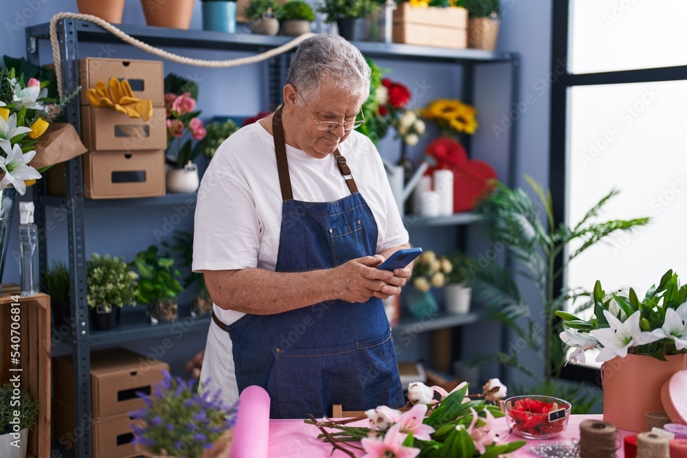 Middle age grey-haired man florist smiling confident using smartphone at florist Middle age grey-haired man florist smiling confident using smartphone at florist