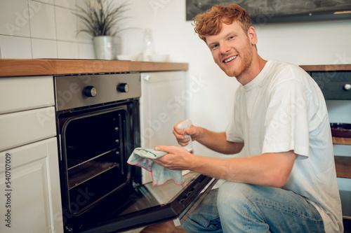 Ginger man in casual clothes near the oven in the kitchen