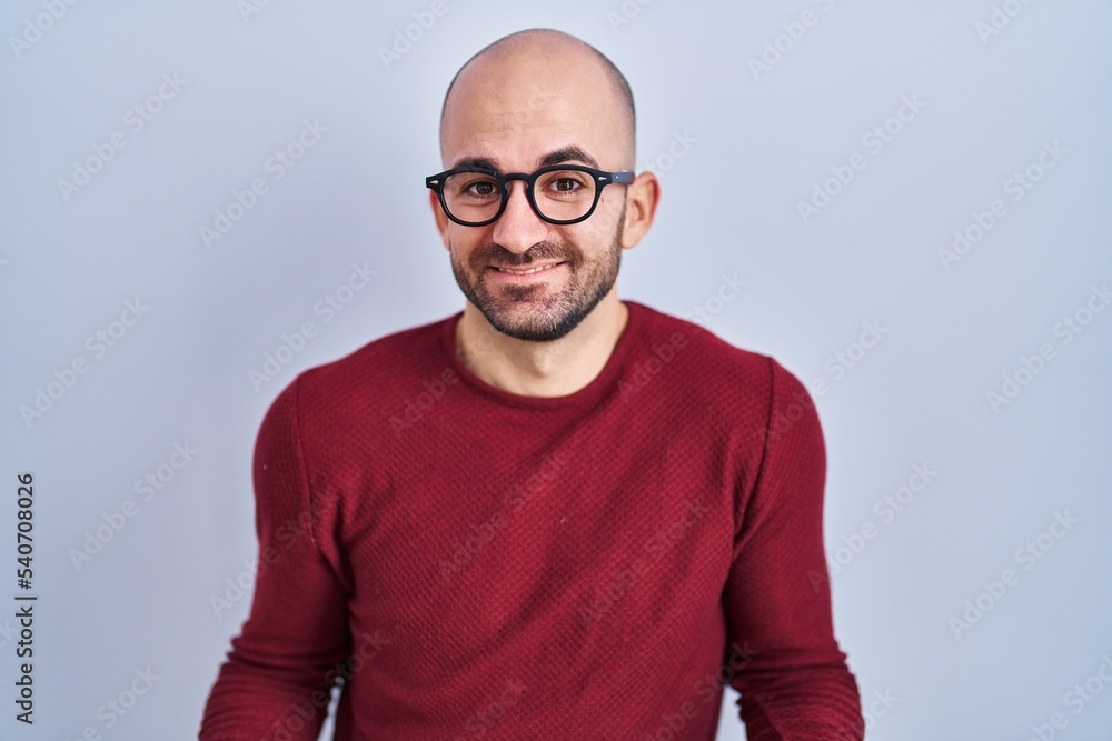 Young bald man with beard standing over white background wearing glasses smiling cheerful with open arms as friendly welcome, positive and confident greetings Young bald man with beard standing over white background wearing glasses smiling cheerful with open arms as friendly welcome, positive and confident greetings