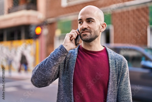 Young man smiling confident talking on the smartphone at street