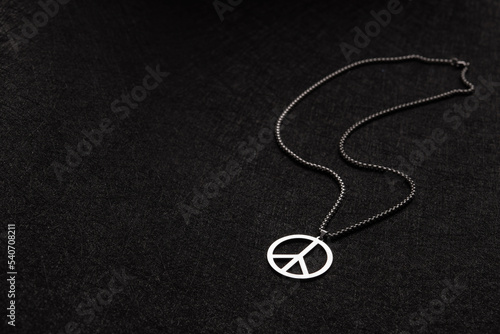 Necklace with a mark of peace on a black old background.